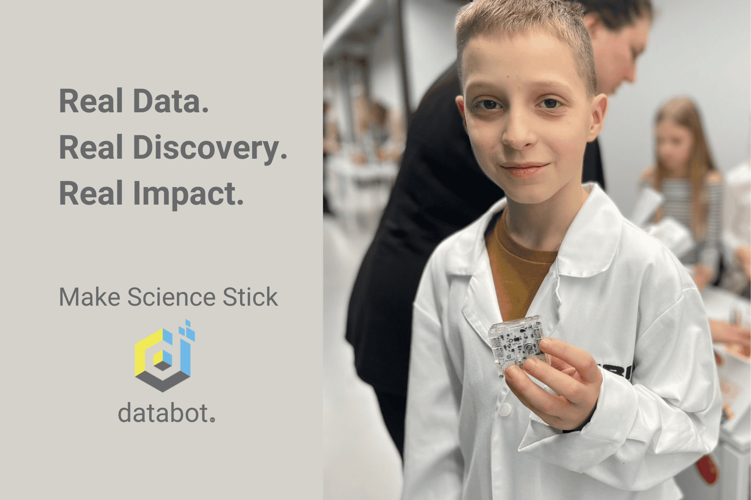 A 10 year old boy in a white lab coat holding a databot and looking into the camera as if he really knows something powerful.